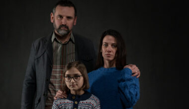 Refugee family with one child looking at camera on black background