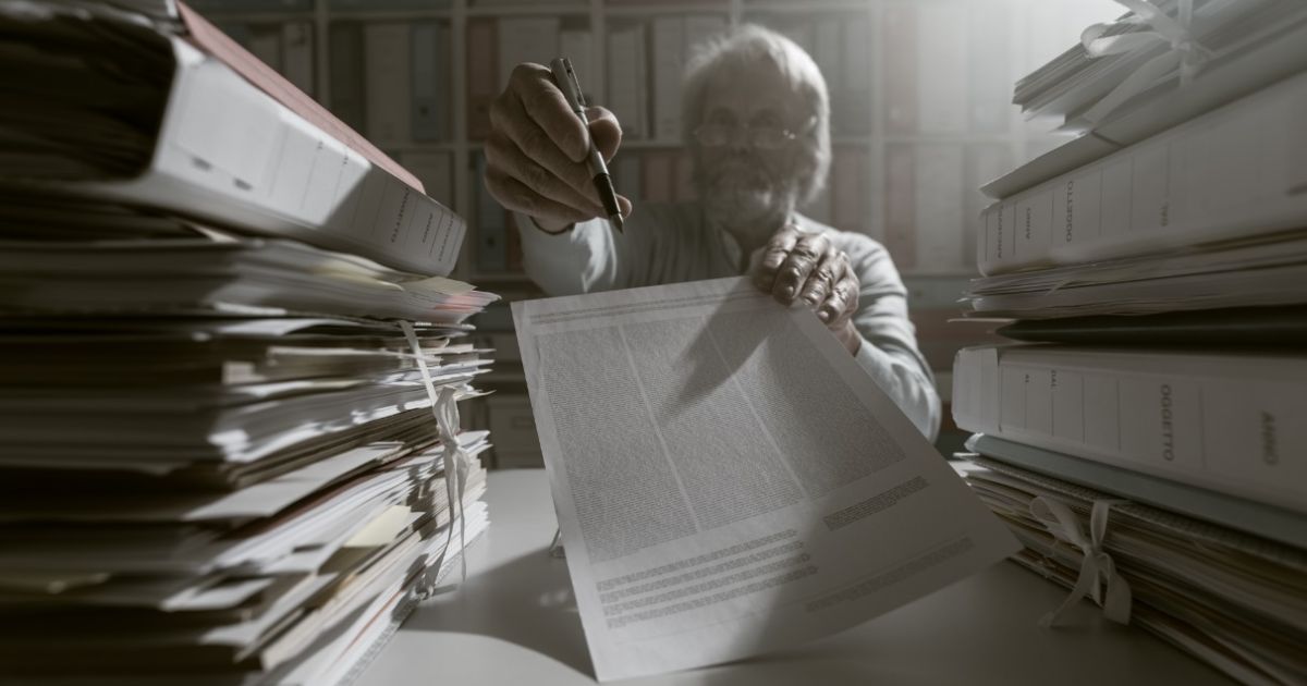 Lawyer reviewing an administrative file surrounded by stacks of case documents, illustrating the written-argument stage of an administrative recourse in Cyprus.